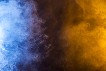 Blue and yellow smoke on a dark background. Texture and desktop picture