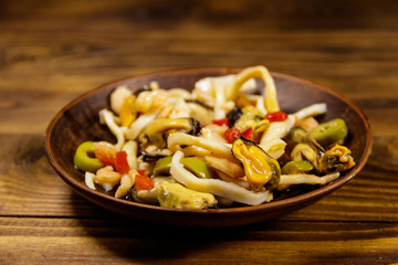 Seafood salad with shrimp, squid and mussels on wooden table