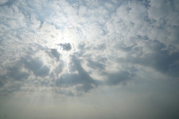 Blue sky background with white clouds and sun ray