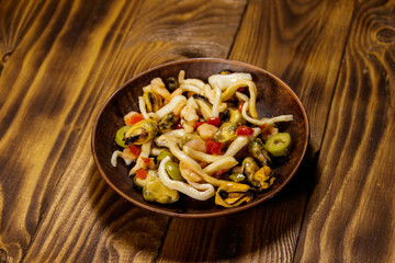 Seafood salad with shrimp, squid and mussels on wooden table