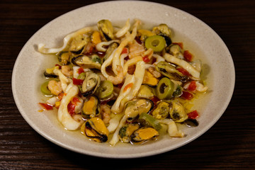 Seafood salad with shrimp, squid and mussels on wooden table