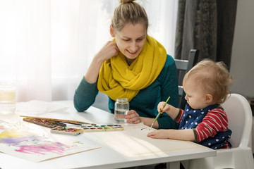 mother and her daughter drawing with watercolor at home