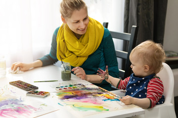 mother and daughter doing watercolor painting - girl looking at her dirty hand