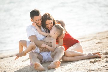 Happy family having fun at the beach. Mom, dad, son and little daughter at the sea shore. Cheerful family