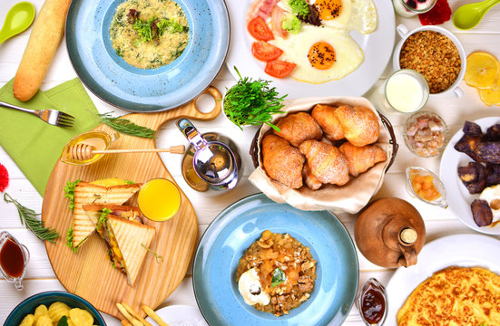 A big breakfast feast on a white wooden table in a sunny morning. Buffet breakfast in a hotel.
