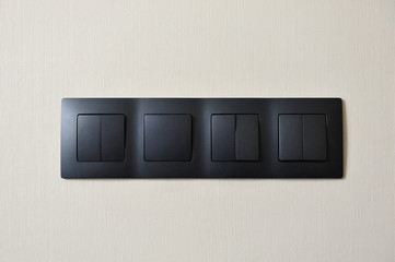 Four light switches of black plastic combined into one