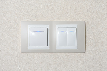 Two light switches combined in one. Switches of light with blue illumination