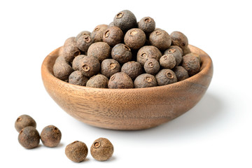 dried pimento berries in the wooden plate, isolated on white background