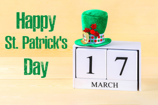 A green hat on a wooden table. St.Patrick 's Day. A wooden calendar showing March 17.