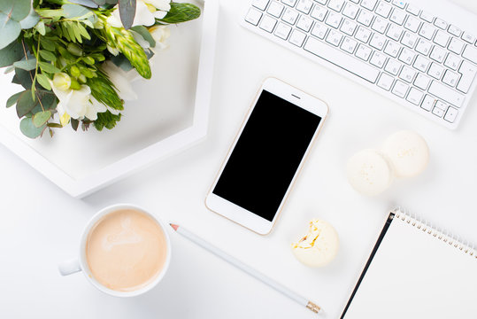 Lady bloggers work desk with fresh bouquet of flowers and macaro