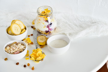 Breakfast in a jar: cornflakes, banana, fresh berries, granola, yogurt on a light background. The concept of healthy eating, high-carbon Breakfast.