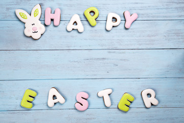 Cookies lettering Happy Easter with rabbit card on wooden blue background.