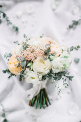 Wedding composition with bridal bouquet of eucalyptus branches, rose flowers on white textile background. Flat lay, top view festive wedding fashion concept.