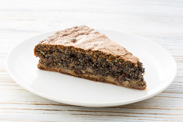 Slice of Austrian poppy seed cake on wooden white background