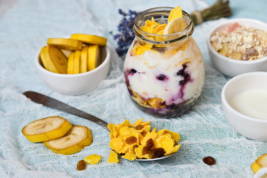 Breakfast in a glass jar: homemade granola, banana, fresh berries, yogurt on a light textile background with a bouquet of lavender. The concept of healthy eating, high-carbon Breakfast.
