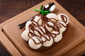 Chocolate egg ith filling for Easter on wooden background