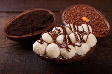 Chocolate egg ith filling for Easter on wooden background