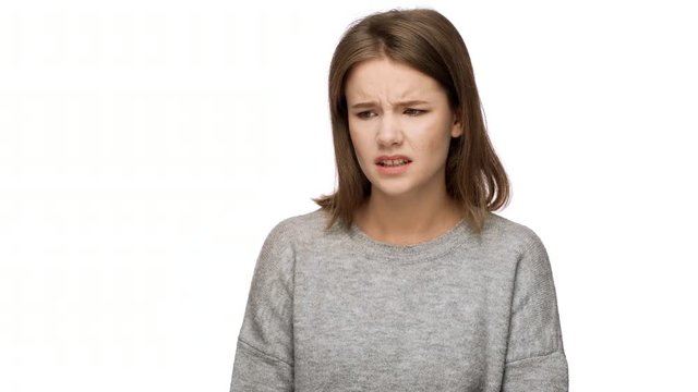 Portrait of discontented female in casual clothes feeling aversion looking with displeased expressions and demonstrating her disgust, over white background. Concept of emotions