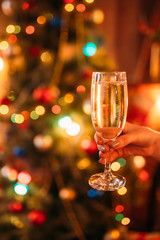 Female hand holds glass with champagne, christmas