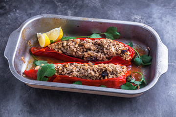 Stuffed paprika peppers in iron cooking pot on dark rustic kitchen table background, top view