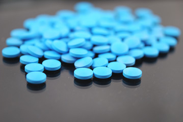 Bright blue round tablets close-up on black background