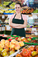Saleswoman near shelves of vegetables