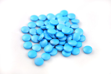 Bright blue round tablets closeup on white background