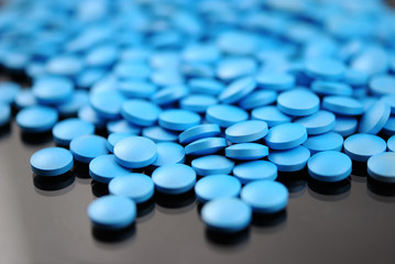 Bright blue round tablets closeup on black background
