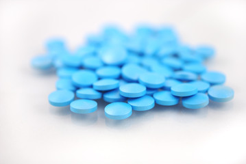 Fototapeta na wymiar Bright blue round tablets closeup on white background