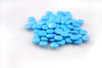 Bright blue round tablets closeup on white background