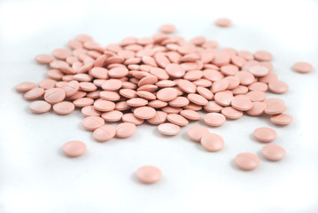 Light pink tablets closeup on white background