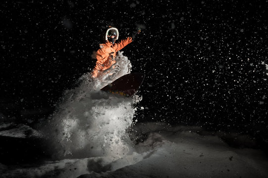 Man breathtakingly snowboarding at night under the snow
