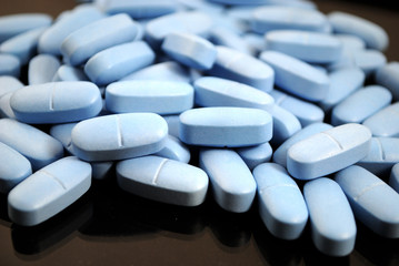 Light blue oval tablets closeup on black background
