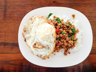 Thai food, Rice topped with stir-fried pork and basil. Top view with wooden table.