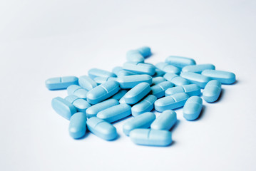 Blue oval tablets closeup on white bakground
