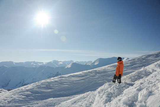 Snowboarder standing and enjoying mountain landscape in Gudauri, Georgia