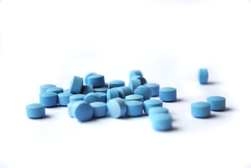 Small round blue pills closeup on white background