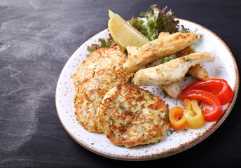 Fish with zuccini pancakes  and  fresh pepperon dark background