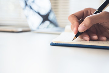 closed up businessman writing on notebook on wooden table, Concept finance planing and analyzes management.