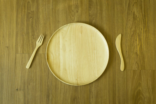 wooden circle plate on the wooden table top view with folk and knift paddle