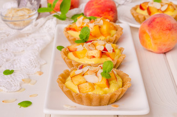 Tartlets with custard, fresh peaches and almonds