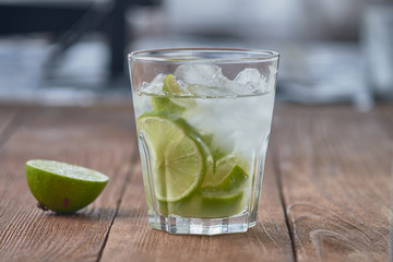 Caipirinha with ice and lime on a wooden table. Summer soft drink.