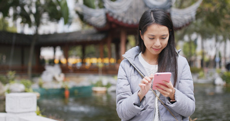 Woman use of smart phone in chinese garden
