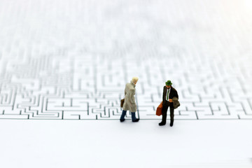 Miniature people: Businessman standing on start of maze. Concepts of finding a solution, problem solving and challenge.