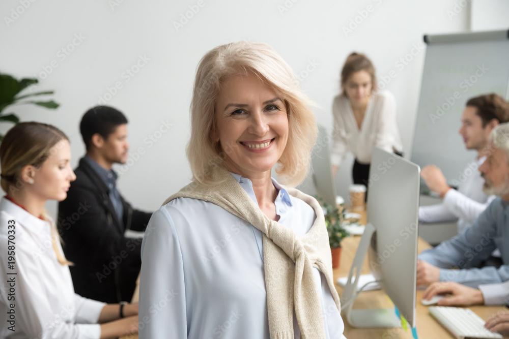 Poster smiling female aged company executive or team leader looking at camera, happy senior businesswoman t