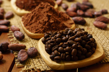 Coffee beans, cacao powder, cocoa nibs, on wooden plates on burlap