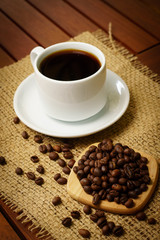 Cup of black coffee and coffee beans on burlap