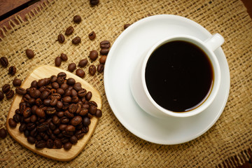 Cup of hot black coffee and coffee beans on burlap