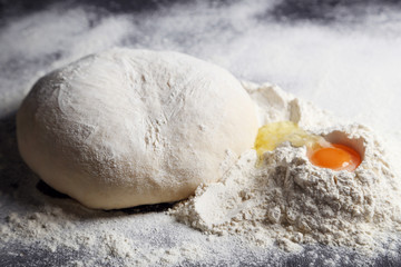 Raw dough with egg on black wooden table