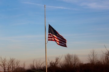 The united state flag at half mast in the evening sky.